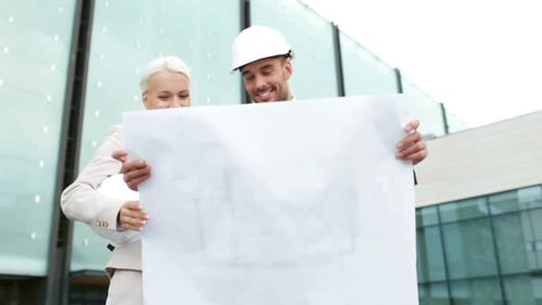 Smiling business partners discussing city architecture blueprint development