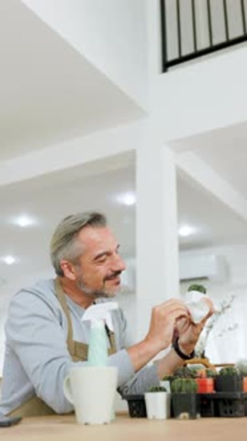 Man Carefully Examining Cactus in an Indoor Setting