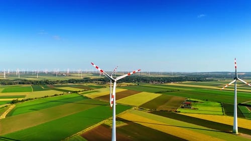 Spectacular green fields in the picturesque countryside. Windfarms produce green energy. Aerial view