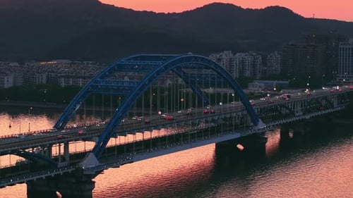 Beautiful Sunset View of a Bridge Over a River with Cars Passing By and Vibrant Colors Illuminating