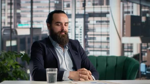 Bearded Man Reviews Financial Documents in Office