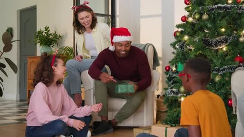 Exchanging gifts by decorated tree, Diverse family celebrating Christmas together, smiling joyfully