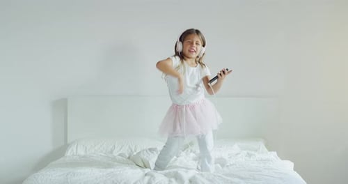 Enthusiastic Girl Singing and Dancing on Bed
