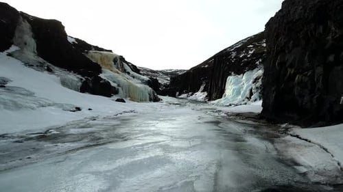 Icy River Flows Through a Snowy Canyon