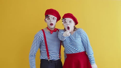 Man and a Woman Mimes Act Out a Scene on a Plain Yellow Background