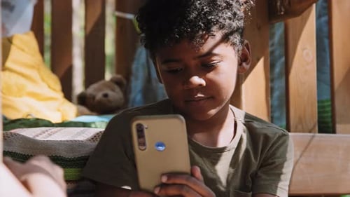 Pensive Boy Using Phone Inside Wooden Structure