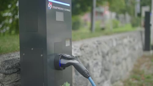 Close up of a modern electric car charger station with a charger being attached to a silver chaging