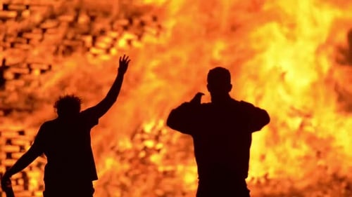 A huge celebration bonfire in Belfast. Bonfire collapses. People watch on and celebrate by dancing a