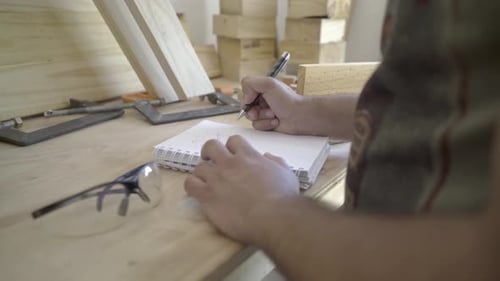 Nahaufnahme eines Handwerkers, der in seiner Werkstatt einen Projektentwurf skizziert