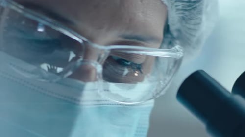 Medical Worker Looking Into Microscope in Lab