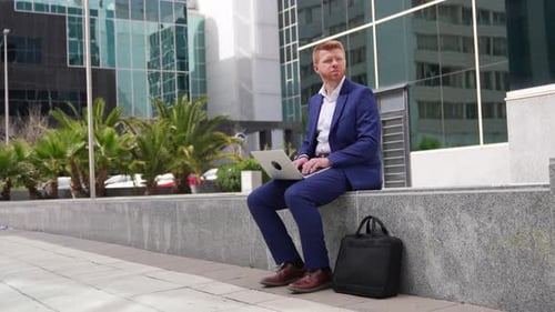 Man Working on Laptop Outdoors in Urban Setting