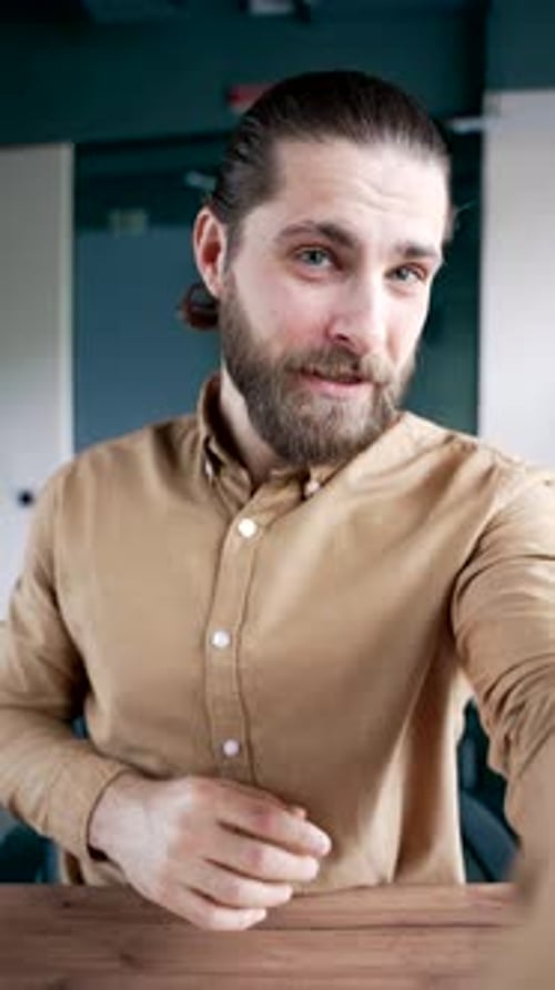 POV Vertical. Smiling businessman talking on video call using a phone in business office. Handsome