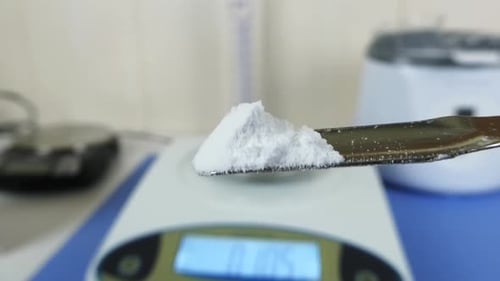 Gros plan des mains gantées d'un technicien de laboratoire effectuant un test de contrôle qualité sur de l'acide hyaluronique
