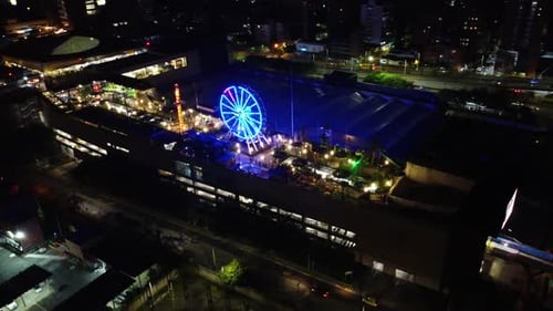 Circular aerial view of an amusement park at night with lights and people enjoying