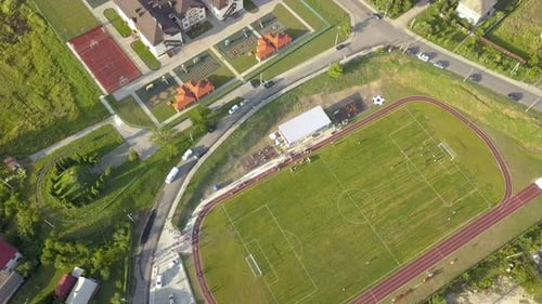 Aerial View of a Football Field on a Stadium Covered with Green Grass in Rural Town Area