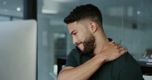 4k video footage of a young businessman suffering from neck pain while working late