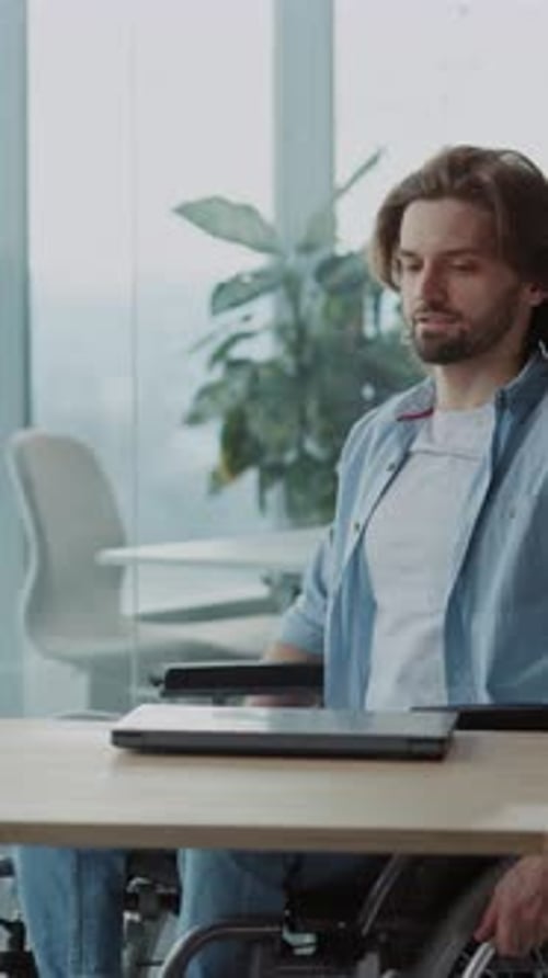 Young Adult Man in Wheelchair Opens Laptop