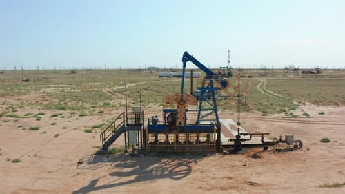 Oil Pump Jack Operating in Wide Desert Field Under Clear Blue Sky