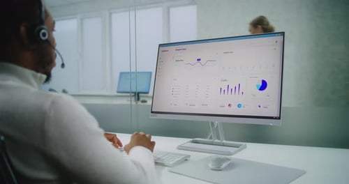 Un spécialiste du marketing afro-américain parle d'un casque avec un client fonctionne sur ordinateur