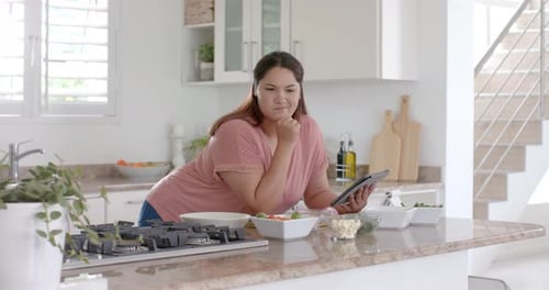 Woman Follows Recipe on Tablet in Bright Kitchen