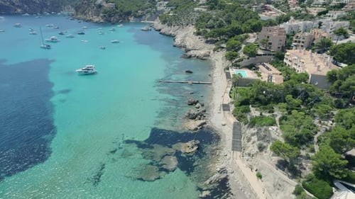 Aerial flyover Mallorca coastline with beautiful clear waters and hotels perched on hillside