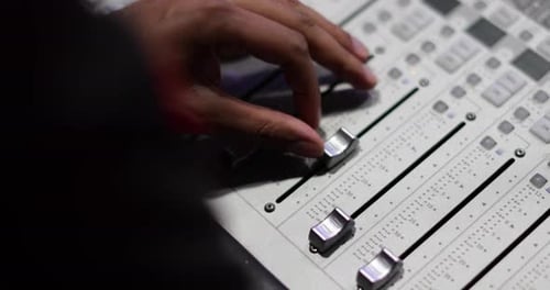 Closeup hands working a control mixer in a recording studio