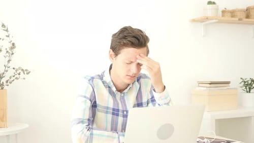 Tired Young Man Having Headache in Office