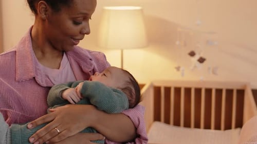 Loving Mother Holds Newborn Infant in Nursery