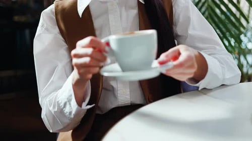 Young Woman Holding Cup of Coffee in Cafe