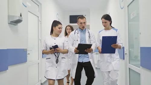 Medical Team Walking Through Hospital Hallway Discussing Patient
