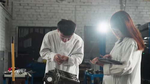 Inventors Measuring Engine Component and Recording Data in Automotive Workshop