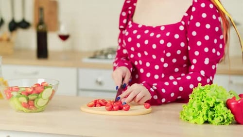 Woman Cuts Tomatoes For Salad Preparation in Kitchen