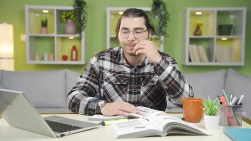 Adult Studying at Desk with Laptop and Book