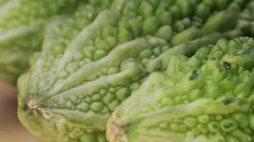 Une gourde amère, un légume souvent utilisé comme ingrédient en cuisine, est posée sur une table en bois.
