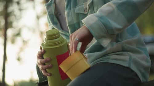 Person Opens Thermos in Sunny Outdoor Setting