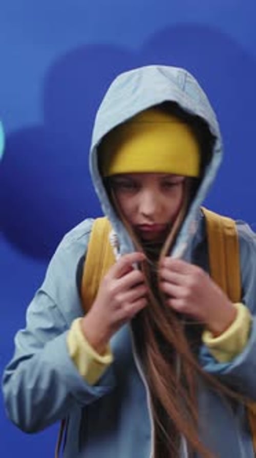 Une jeune fille portant une tenue colorée pose en souriant sur un fond bleu vif