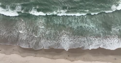 High Angle Drone View of Rough Ocean Waves Hitting Dark Beach Sand