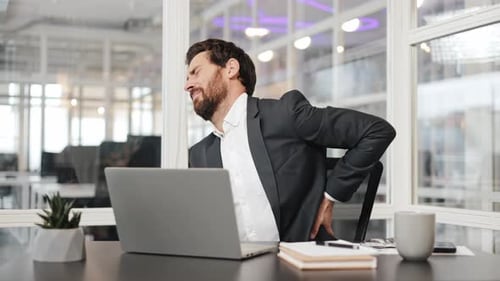 Businessman Experiences Back Pain While Working in Office