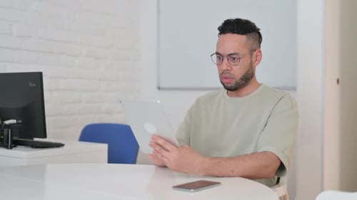Man with Tablet Showing Shocked Expression Indoors