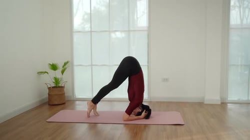 Athletic Woman Performs Yoga Headstand Pose Indoors