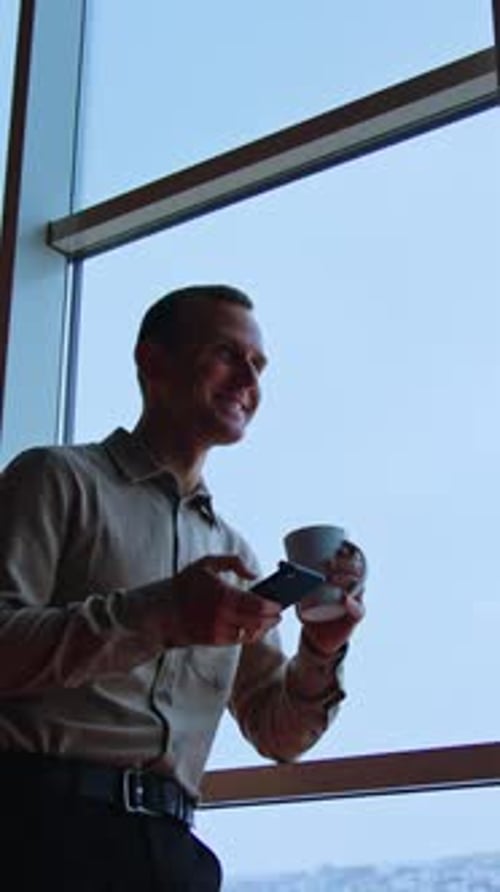 Man Using Cellphone near Window in Urban Setting