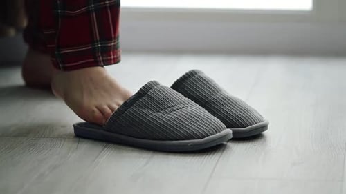 Feet in Slippers on Wood Floor