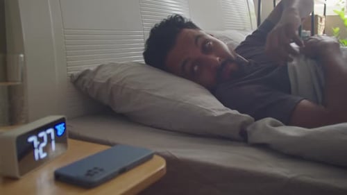 Man Wakes and Checks Phone in Bedroom