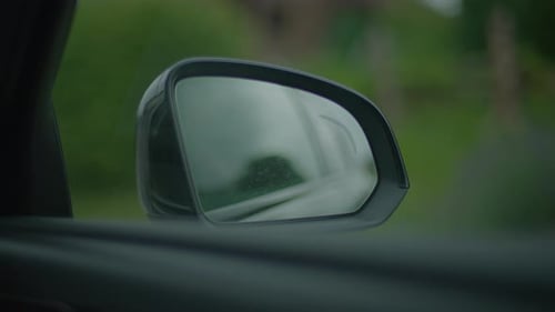 Closeup of a Cars Side Mirror with Rainwater Droplets Blending Nature and Urban Transportation