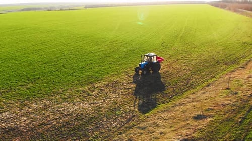 Drone Footage Tractor Spreading Artificial Fertilizers in Green Field