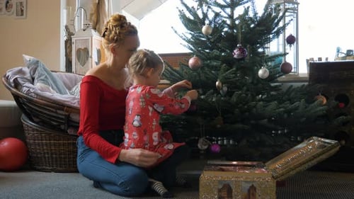 Mother and Child Decorating Christmas Tree in Home