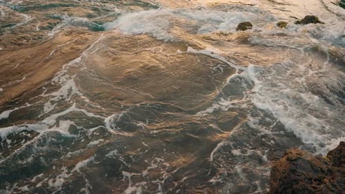 Close up shot of rough ocean waves crushing against the volcanic rocky coastline. Colorful turquoise