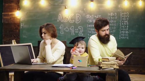 Family Doing Schoolwork at Desk in Front of Chalkboard