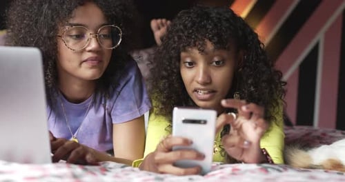 Friends Using Technology Lying on Bed Together