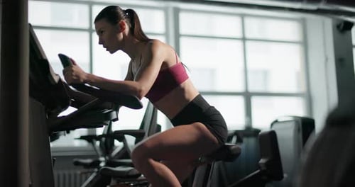 A Young Beautiful Brunette Girl in Sportswear Exercises on a Simulator in the Gym Doing Cardio